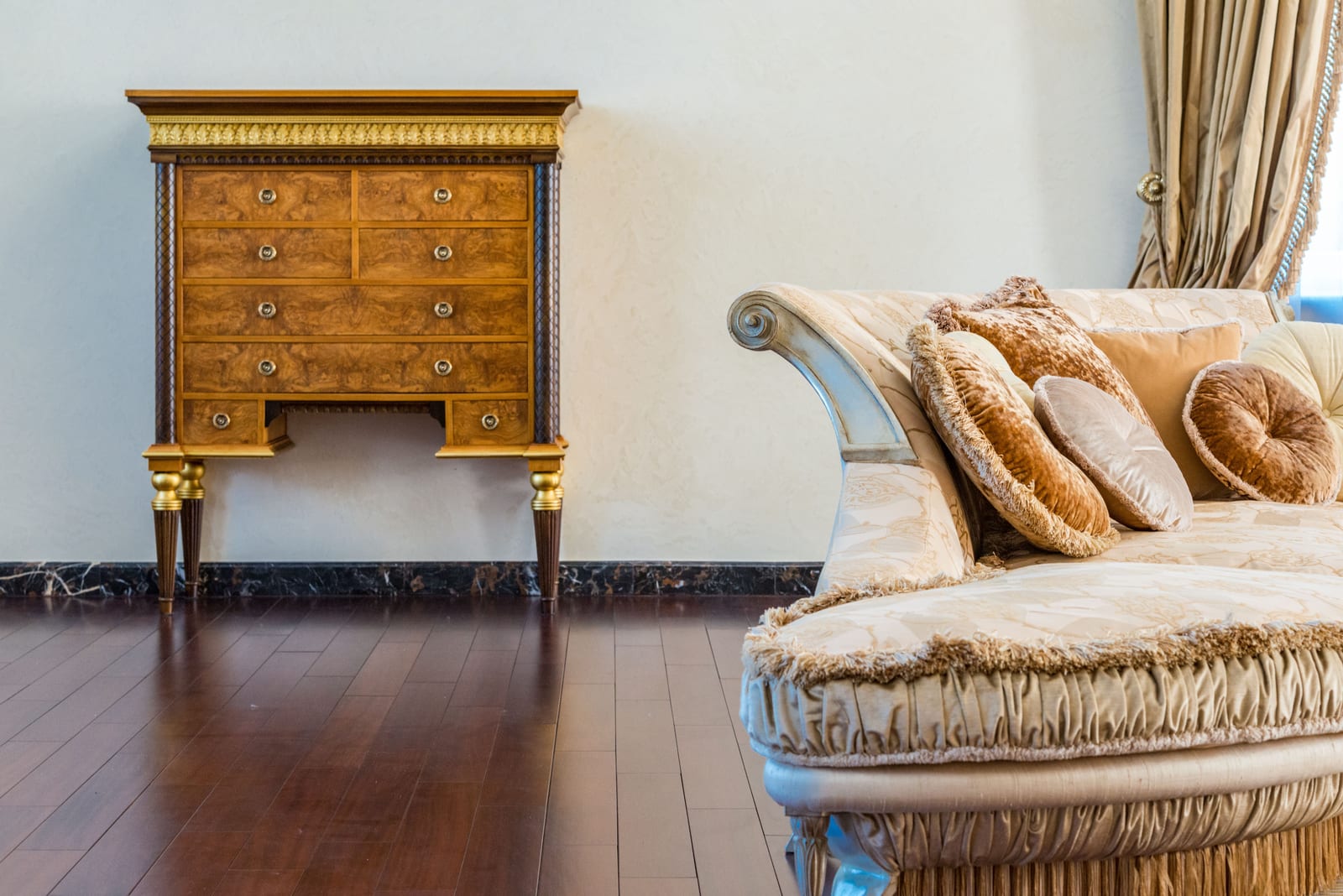 An antique chest and a gilt frame in a quiet estate room.